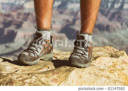 Mountain hike man hiker trekking travel walking with hiking shoes closeup of feet standing on rock. 81147082