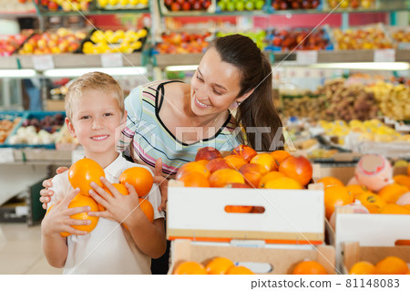mother with little boy buying oranges at store 81148083