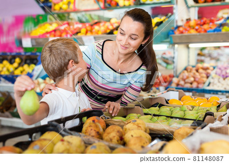 Cheerful mother with little boy buying pears and apples at store 81148087