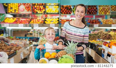 mother with little boy buying fruits and vegetables at store 81148275