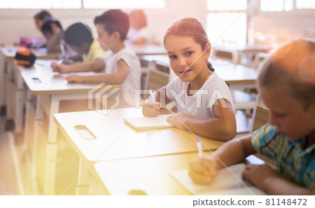 Tween schoolgirl looking at camera with smile in classroom Tween schoolgirl looking at camera with smile in classroom 81148472