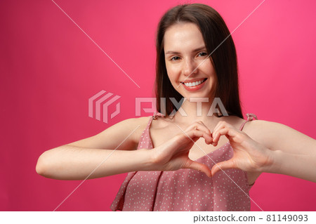Smiling young woman gesturing heart sign with hands showing love 81149093