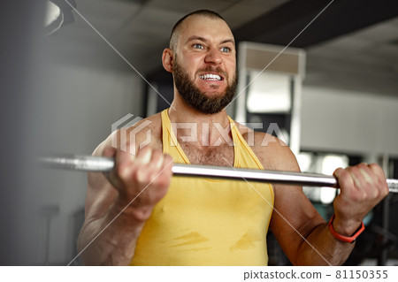 Cheerful smiling man bodybuilder standing in a gym Cheerful smiling man bodybuilder standing in a gym 81150355