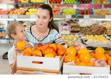 Portrait of happy woman and her little son choosing oranges at shop 81150453