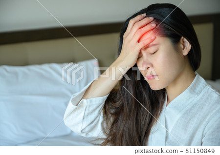 Portrait of young Asian woman sitting on bed and suffering from headache. Headache maybe occurs from stress, tension or migraine etc. Portrait of young Asian woman sitting on bed and suffering from headache. Headache maybe occurs from stress, tension or migraine etc. 81150849