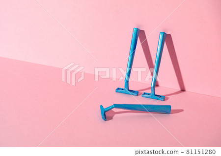 Blue disposable razors on pink paper background 81151280
