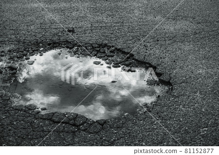 Rainwater and clouds reflected in the dents of the asphalt pavement Rainwater and clouds reflected in the dents of the asphalt pavement 81152877