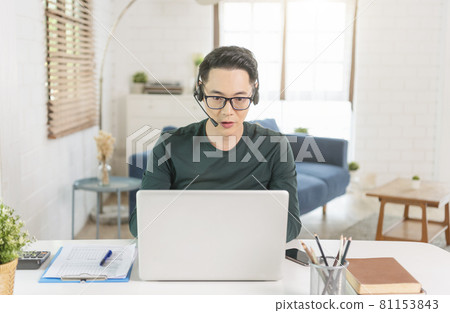Smiling handsome asian businessman working remotely from home. He is webinar video conference. 81153843