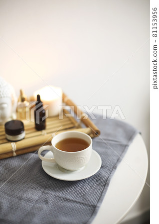 Round table in spa salon with cup of herbal tea next to bamboo tray with different aromatic oils Round table in spa salon with cup of herbal tea next to bamboo tray with different aromatic oils 81153956