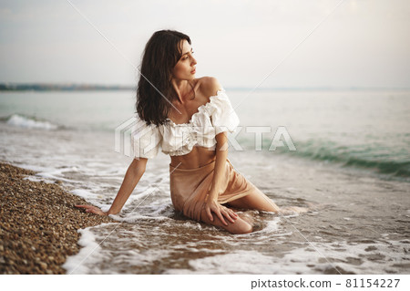 Young relaxed woman sitting all alone on empty beach 81154227