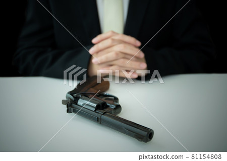 Unrecognizable businessman put the revolver hand gun on the table. Unrecognizable businessman put the revolver hand gun on the table. 81154808