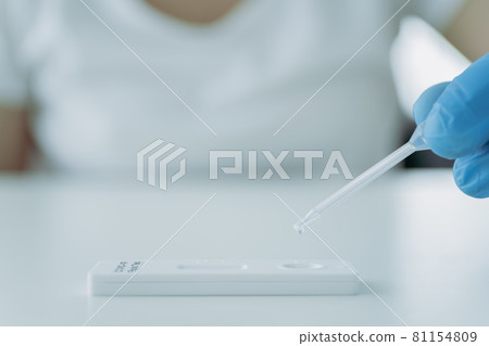Unrecognizable woman testing a COVID-19 antigen at home. Unrecognizable woman testing a COVID-19 antigen at home. 81154809