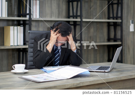 Sad Asian businessman holds his temple with both hands, sitting in the office. The concept of unemployed, sadness, depressed and human problems. Sad Asian businessman holds his temple with both hands, sitting in the office. The concept of unemployed, sadness, depressed and human problems. 81156525