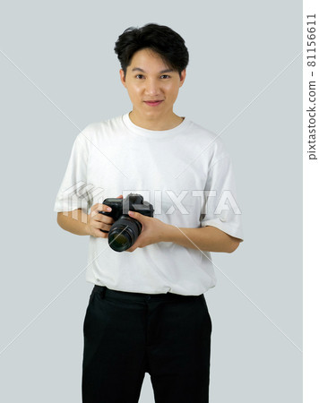 Asian photographer holding DSLR camera with both hand while standing in a white photography scene. The atmosphere in the photo studio. Asian photographer holding DSLR camera with both hand while standing in a white photography scene. The atmosphere in the photo studio. 81156611