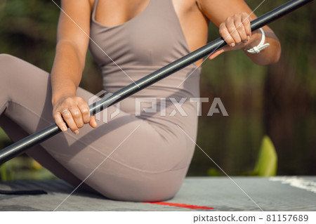 Cropped image of Caucasian woman, sportsman, tourist on paddle board, SUP, practicing alone. Active life, sport, leisure activity concept 81157689