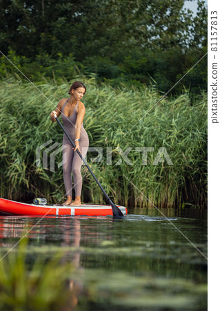 Young Caucasian woman, sportsman, tourist standing on paddle board, SUP, practicing alone. Active life, sport, leisure activity concept Young Caucasian woman, sportsman, tourist standing on paddle board, SUP, practicing alone. Active life, sport, leisure activity concept 81157813