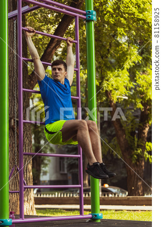 One young handsome caucasian man in sportswear training, exercising on sports ground outdoors on bright summer day. One young handsome caucasian man in sportswear training, exercising on sports ground outdoors on bright summer day. 81158925