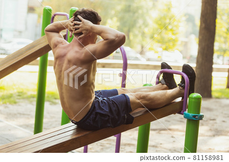 One young handsome caucasian man in sportswear training, exercising on sports ground outdoors on bright summer day. One young handsome caucasian man in sportswear training, exercising on sports ground outdoors on bright summer day. 81158981