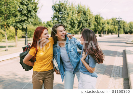 Schoolgirls walk along the park alley to school, talk and laugh. The concept of training and education. Back to school 81160590