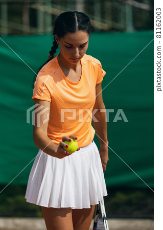 Beautiful young sportswoman, professional tennis player with racket practicing on clay tennis court in summer day. Beautiful young sportswoman, professional tennis player with racket practicing on clay tennis court in summer day. 81162003