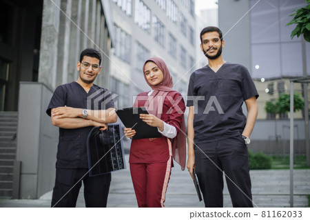 Three doctors, Muslim lady in hijab and two Arabian men, working in front of the clinic Three doctors, Muslim lady in hijab and two Arabian men, working in front of the clinic 81162033