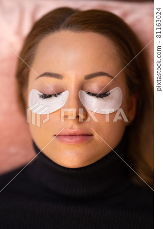 Customer With Cotton Pads During Eyelash Extension Procedure Customer With Cotton Pads During Eyelash Extension Procedure 81163024