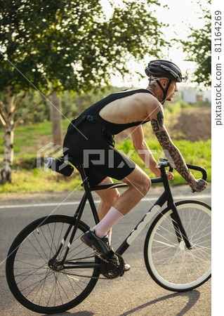 Young male cyclist riding a road bike in summer day. Action, motion concept Young male cyclist riding a road bike in summer day. Action, motion concept 81164269