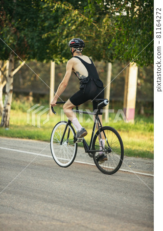 Young male cyclist riding a road bike in summer day. Action, motion concept Young male cyclist riding a road bike in summer day. Action, motion concept 81164272