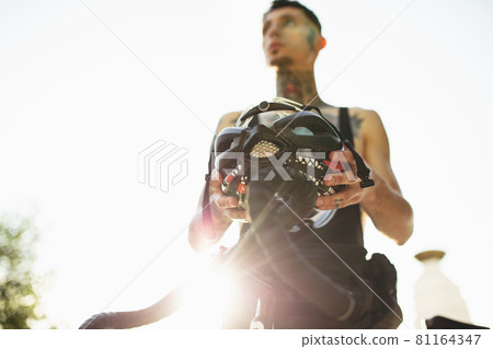Young male cyclist wearing protective helmet before riding a bike. Active lifestyle concept Young male cyclist wearing protective helmet before riding a bike. Active lifestyle concept 81164347