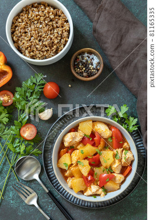 The concept of Diet menu. Homemade turkey or chicken with pineapple sauce and boiled spelled on a dark stone table. Top view flat lay background. The concept of Diet menu. Homemade turkey or chicken with pineapple sauce and boiled spelled on a dark stone table. Top view flat lay background. 81165335