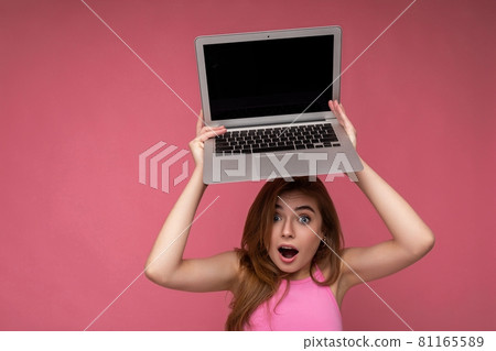 Close-up portrait of Beautiful amazed young woman saying wow with open mouth holding netbook Close-up portrait of Beautiful amazed young woman saying wow with open mouth holding netbook 81165589
