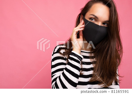 Young beautiful woman in reusable virus protective mask on face against coronavirus isolated on the 81165591