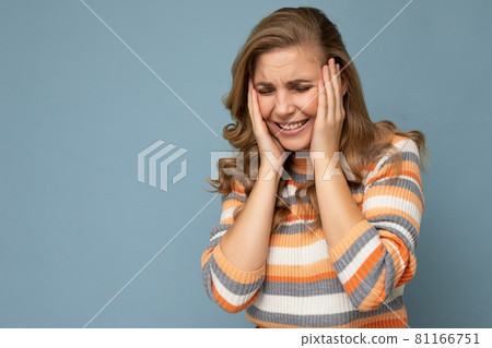 Portrait of young beautiful blonde curly woman with sincere emotions wearing stylish striped sweater Portrait of young beautiful blonde curly woman with sincere emotions wearing stylish striped sweater 81166751