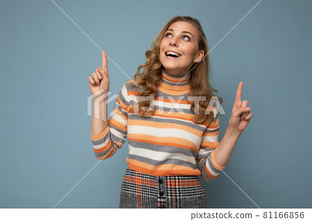 Photo of pretty astonished young woman pointing fingers up at copyspace presenting incredible ads 81166856