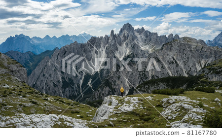 Man hiker standing and admiring stunning beauty of impressive jagged peaks of Cadini di misurina mountain group in Dolomites, Italy, part of Tre Cime di Levaredo national park Man hiker standing and admiring stunning beauty of impressive jagged peaks of Cadini di misurina mountain group in Dolomites, Italy, part of Tre Cime di Levaredo national park 81167780