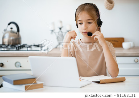 Little caucasian girl in headphones have video call distant class with teacher at home 81168131