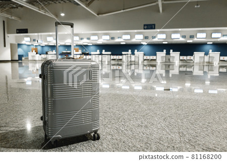 Gray travel suitcase in empty airport hall Gray travel suitcase in empty airport hall 81168200