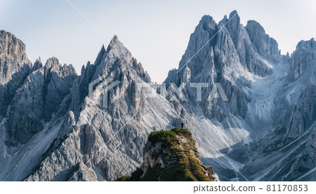 Man hiker standing and admiring stunning beauty of impressive jagged peaks of Cadini di misurina mountain group in Dolomites, Italy, part of Tre Cime di Levaredo national park Man hiker standing and admiring stunning beauty of impressive jagged peaks of Cadini di misurina mountain group in Dolomites, Italy, part of Tre Cime di Levaredo national park 81170853