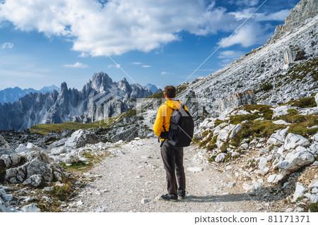 Man in yellow jacket hiking in Tre Cime National park. Cadini di Misurina in the background. Dolomites, Italy, Europe 81171371