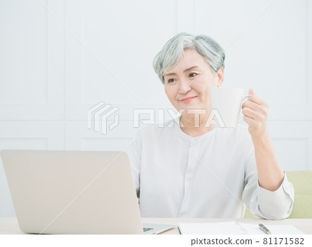 Asian mature woman using wireless laptop to browse internet and drink coffee. Asian mature woman using wireless laptop to browse internet and drink coffee. 81171582
