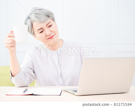 Asian mature woman using wireless laptop to browse internet and drink coffee. Asian mature woman using wireless laptop to browse internet and drink coffee. 81171584
