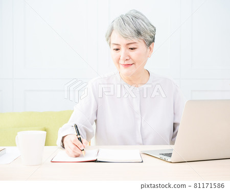 Asian mature woman using wireless laptop to browse internet and drink coffee. Asian mature woman using wireless laptop to browse internet and drink coffee. 81171586