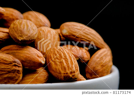 Close up, Almonds nuts in a white bowl on black background. Close up, Almonds nuts in a white bowl on black background. 81173174