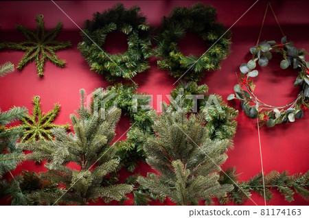 Selection of Christmas wreaths on a red wall in a store. 81174163