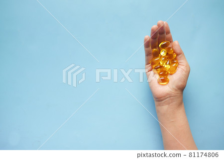 fish oil supplement on hand on blue background fish oil supplement on hand on blue background 81174806