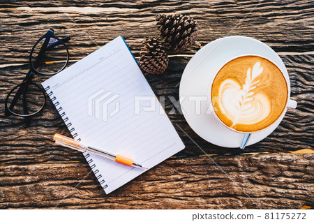 Flay lay of wooden table with blank notebook with other objects (coffee cup, sakura flower and pine cone). Conceptual shot of creative or decoration objects on wooden table. 81175272