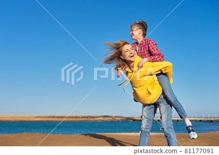 Happy mom and daughter child on seashore, relaxing on sandy beach, autumn winter spring season 81177091