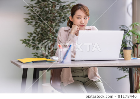 Young woman doing desk work in front of a laptop 81178446