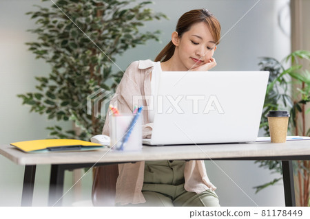 Young woman doing desk work in front of a laptop Young woman doing desk work in front of a laptop 81178449