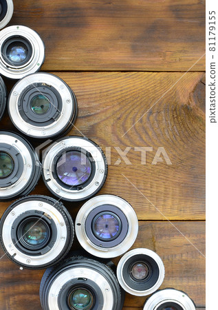 Several photographic lenses lie on a brown wooden background. Space for text 81179155